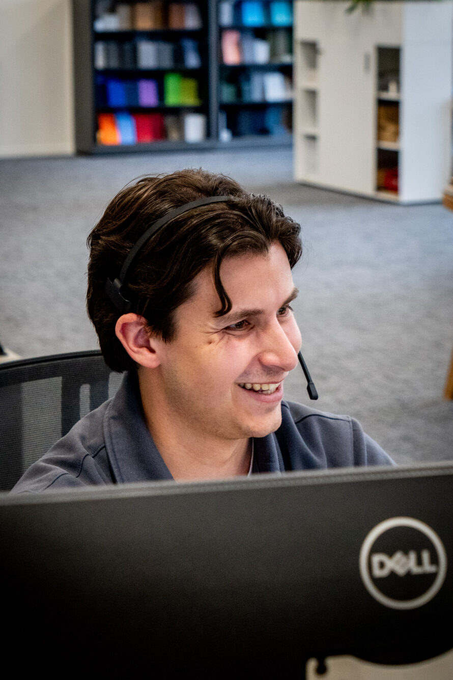 Medewerker met headset werkt achter de computer op de klantenservice-afdeling.