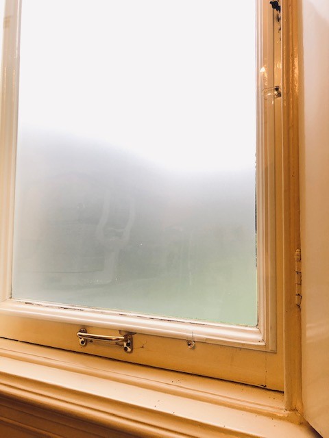 Raam met mat plexiglas in klassiek interieur met houten kozijnen