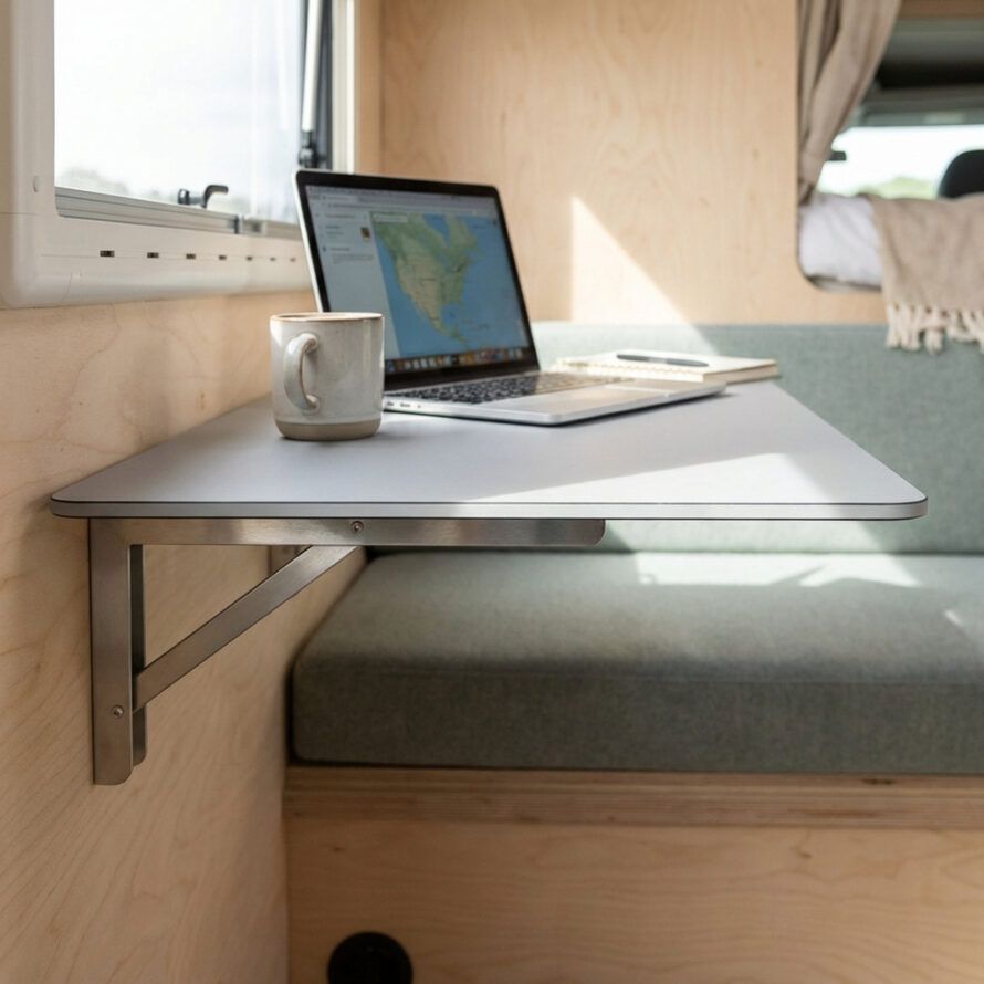 Ultradun campertafelblad bevestigd aan de wand met steunbeugel, ingericht als compacte werkplek met laptop.