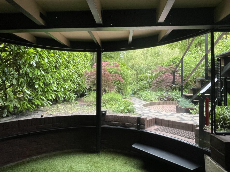 Interieur van een gebogen serre met transparante wanden en groen uitzicht.