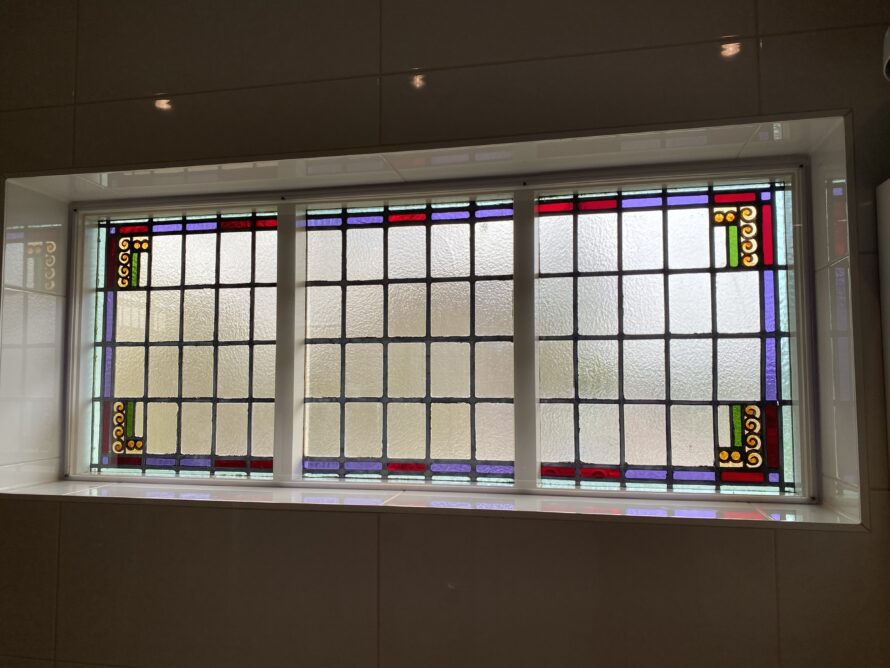 Breed horizontaal glas-in-loodraam met kleine gekleurde accenten.